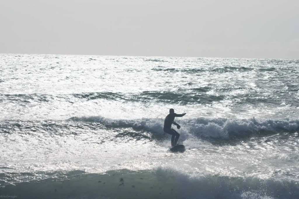 Surfer pe valurile Mării Negre la Vama Veche, România, cu placa de surf