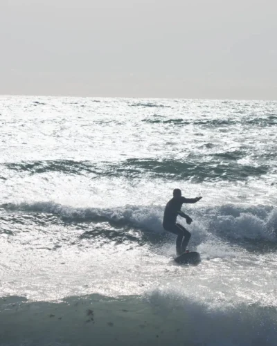 Surfer pe valurile Mării Negre la Vama Veche, România, cu placa de surf