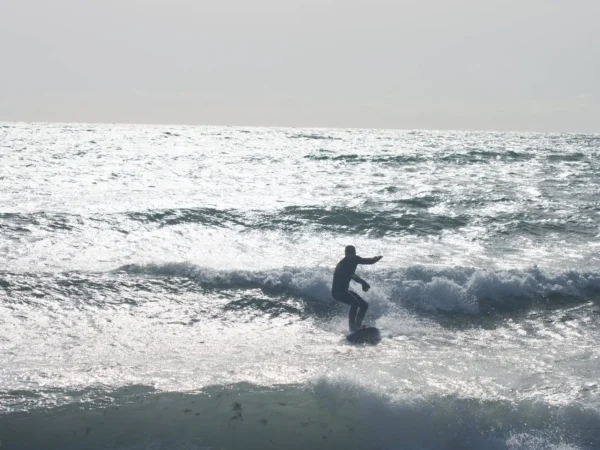 Surfer pe valurile Mării Negre la Vama Veche, România, cu placa de surf