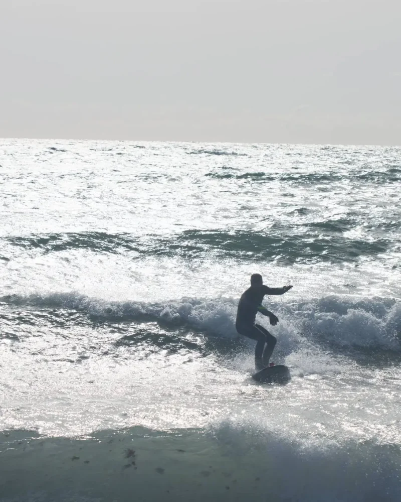 Surfer pe valurile Mării Negre la Vama Veche, România, cu placa de surf